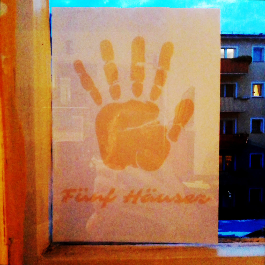 Das Logo von Fünf Häuser Initiative, offenes Handfläche, als Plakat, geklebt am Fenster
