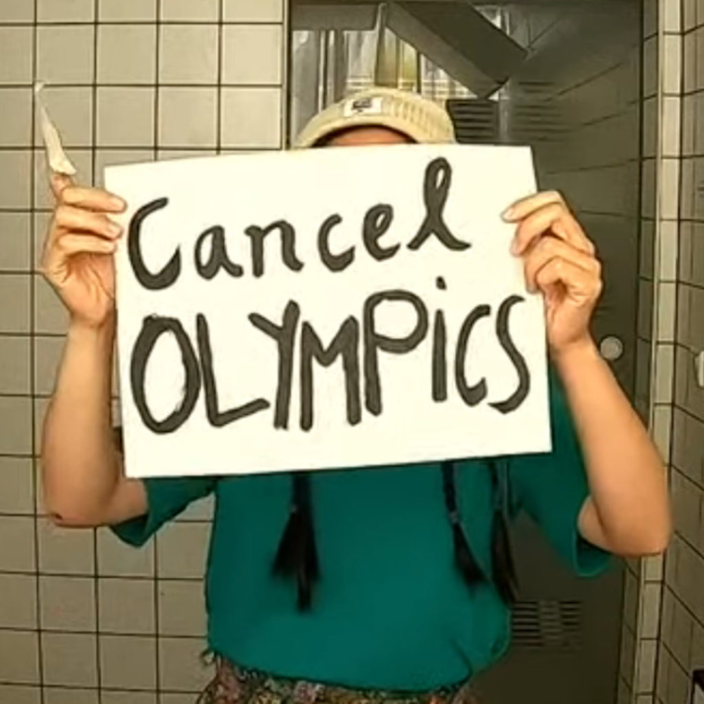 A person holds paper "Cancel Olympics"