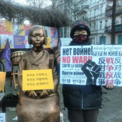 Friedensstatue Ari and Aiko holding sign "No War"