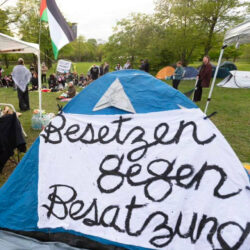 Zelt mit Banner "Besetzen gegen Besatzung" im Hintergrund eine Palästinensische Fahne