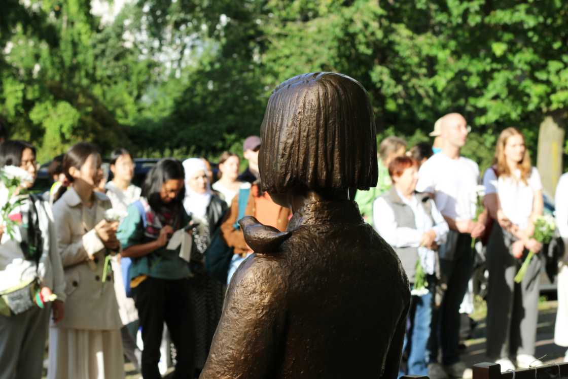 Friedensstatue von hinten , viele Menschen stehen vor ihr.