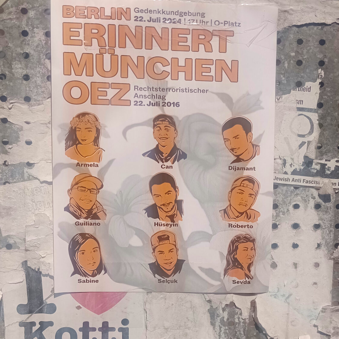 Berlin Erinnert München OEZ. Flyer an einer Metalwand. Mit Ilustration von 9 ermordete Menschen, Armela Segashi, Can Leyla, Dijamant Zabërgja, Guiliano Kollmann, Hüseyin Dayıcık, Roberto Rafael, Sabine S., Selçuk Kılıç und Sevda Dağ. Darunter ist ein alter Sticker zu sehen I heart Kotti